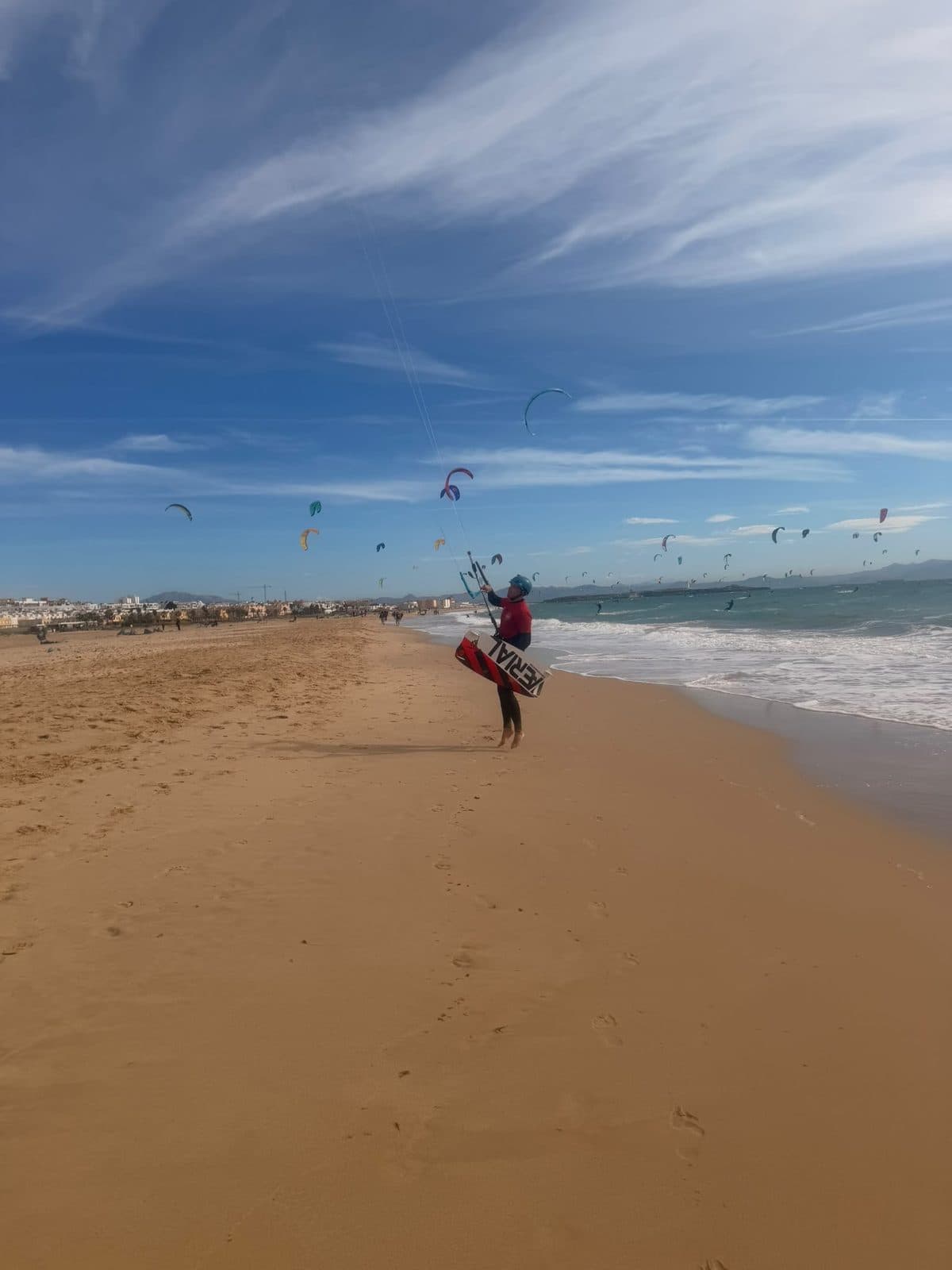 Kiter mit Board steuert den Schirm am Strand