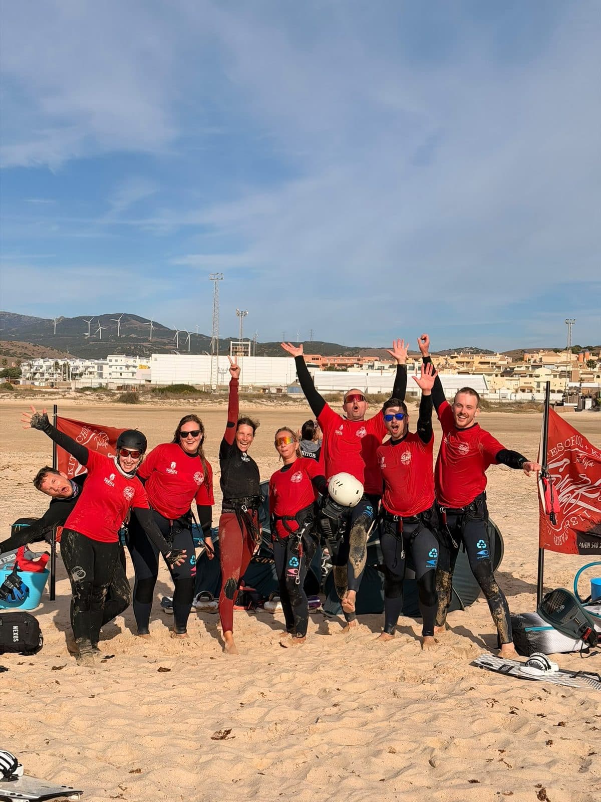 Die Kitegruppe jubelt mit erhobenen Armen am Strand
